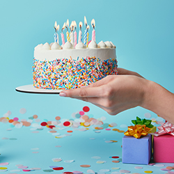 A person holding a birthday cake, representing the idea of birthday fundraisers.