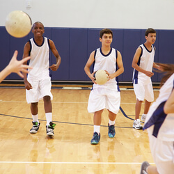Teenagers playing in a dodgeball tournament, illustrating a popular fundraising idea.