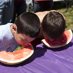 Two children eating watermelon, representing an eating contest.