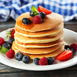 A plate with pancakes and fruit toppings, illustrating the concept of hosting a pancake breakfast for fundraising.