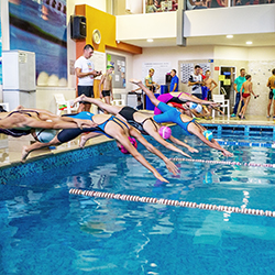 People diving into a pool, representing the idea of a swim-a-thon fundraiser.