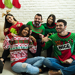 Five people wearing ugly holiday sweaters as part of an ugly sweater party.